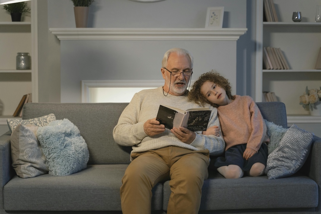 senior man reading book to grandchild