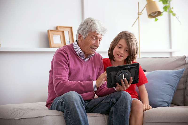 man holding aac device on couch with youth grandson
