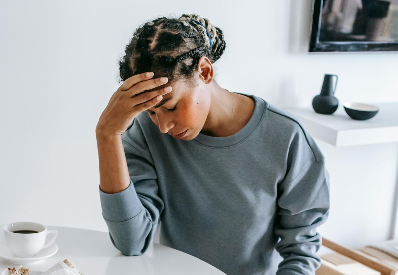 young woman sitting at table with head in hands